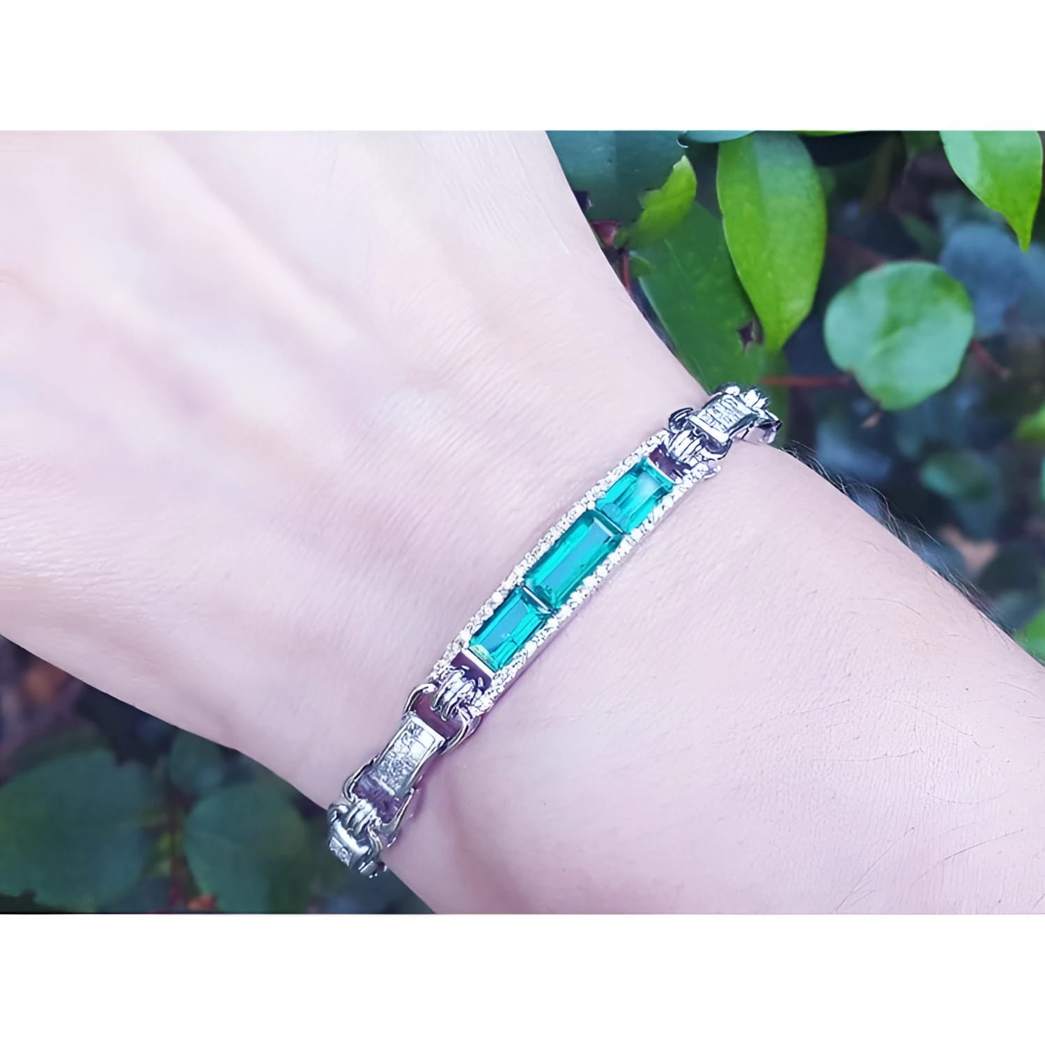 Silver bracelet with vibrant Colombian emeralds and princess-cut diamonds on a wrist.