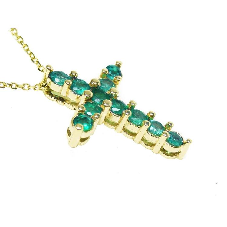 A 14k yellow gold cross necklace pendant with natural colombian emeralds on a side profile view.