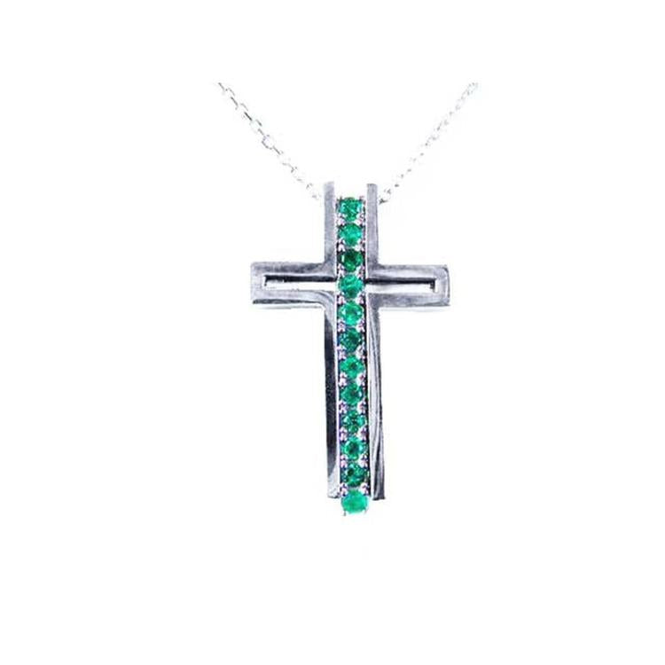 A white gold cross pendant with colombian emeralds on a topside view position.