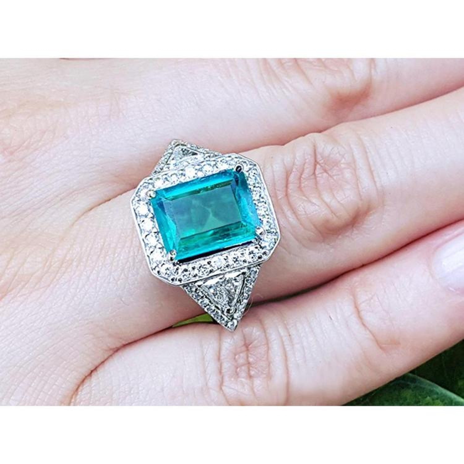 GIA certified 3.98 ct. emerald and diamond ring in 18K white gold, featuring a halo and trillion cut sides.