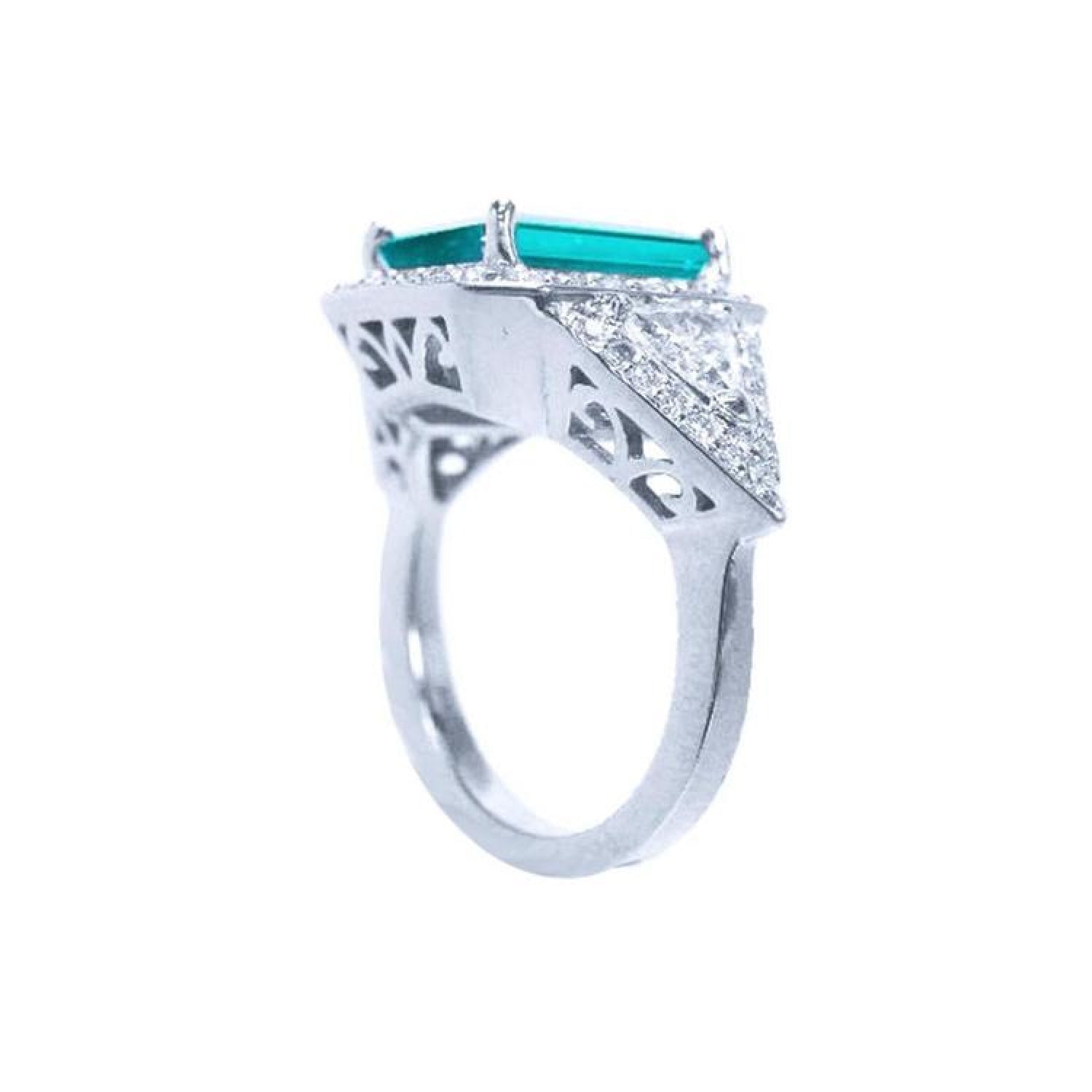 18K white gold ring with a rectangular emerald, diamond halo, and trillion side diamonds.