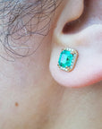 Close-up of an ear wearing emerald stud earring.