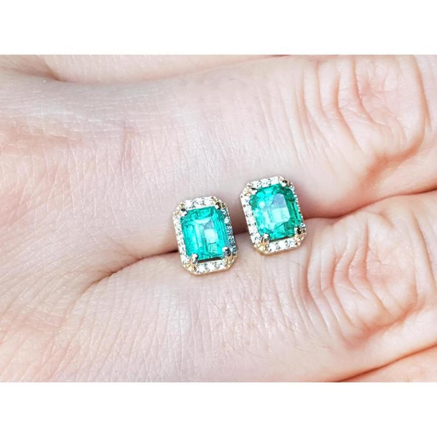 Colombian emerald and diamond halo stud earrings in 14k yellow gold.