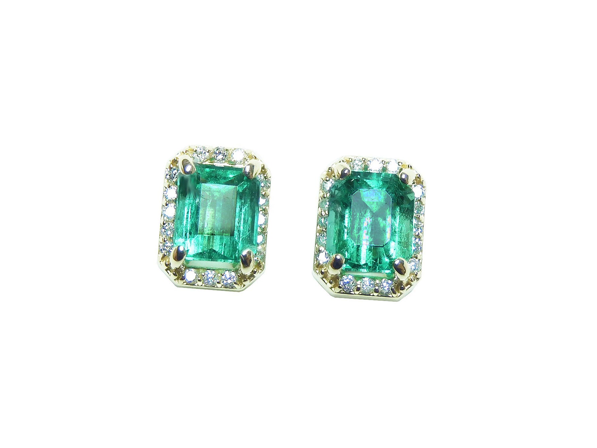 Pair of natural emerald stud earrings halo diamond on a front position, plain top view.