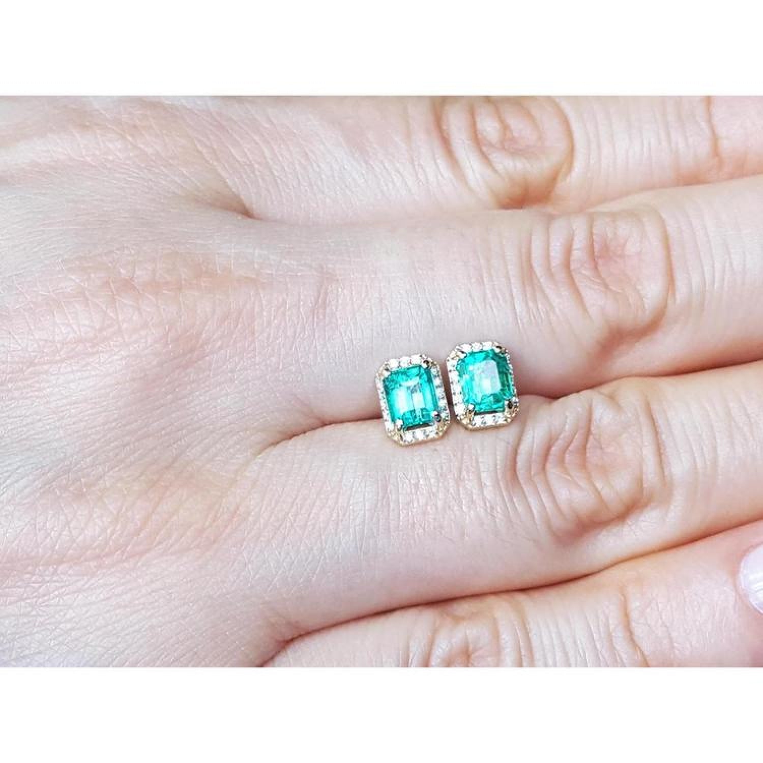 Rectangular Colombian emerald and diamond halo stud earrings in 14k yellow gold.
