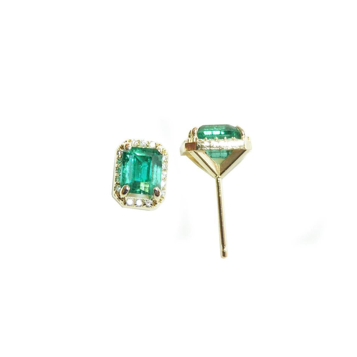 Pair of emerald green gemstone earrings with gold settings on a white background.