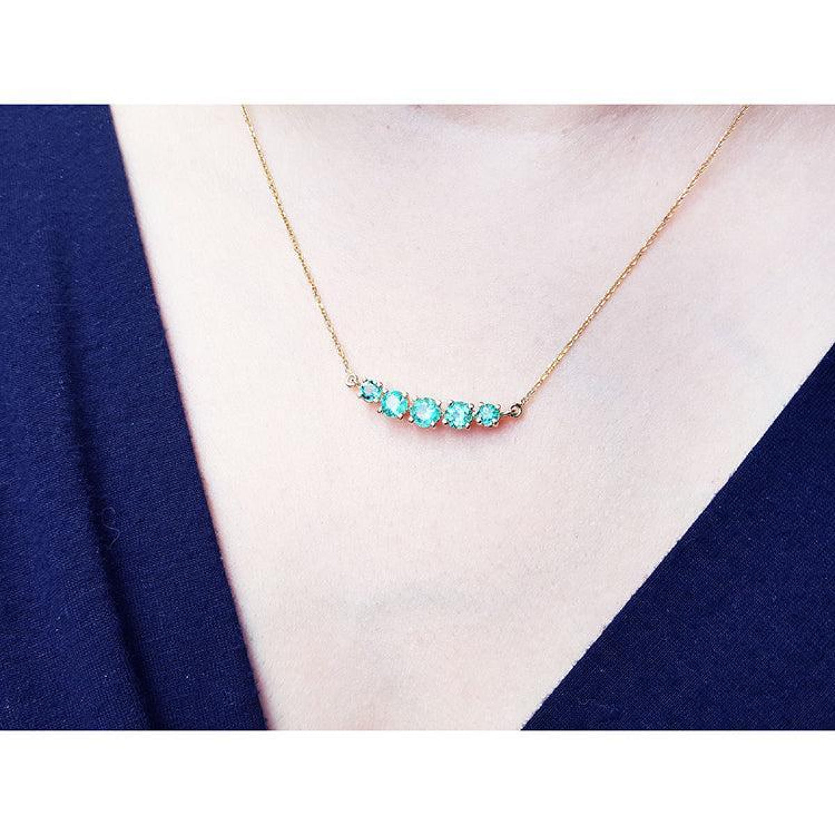 14K gold necklace with five round, medium light green Colombian emeralds, graduating in size.