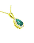A 18k yellow gold pendant with a teardrop natural colombian emerald accented by a halo diamond.