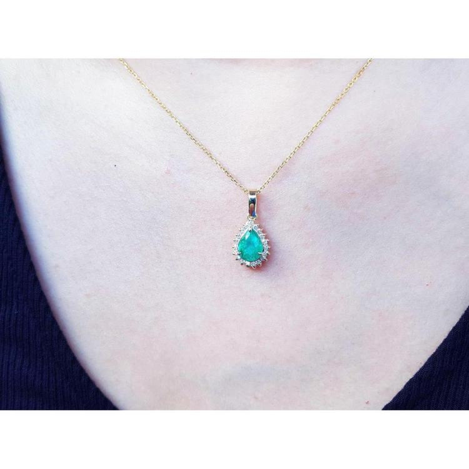 Pear-shaped Colombian emerald pendant with halo diamonds on a 14K yellow gold chain.