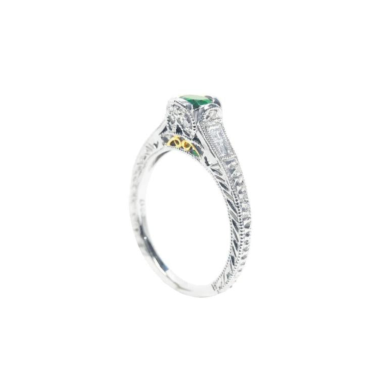 Oval-cut Colombian emerald ring in 14K white gold with baguette diamond accents and intricate filigree.