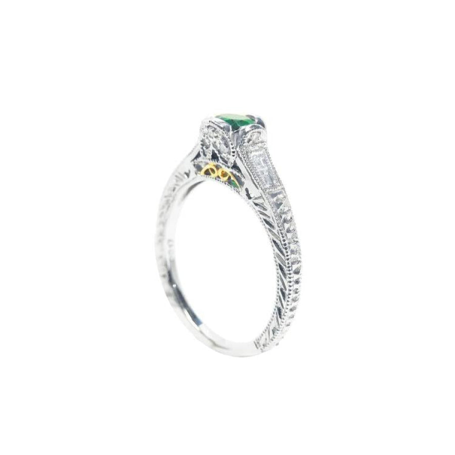 Oval-cut Colombian emerald ring in 14K white gold with baguette diamond accents and intricate filigree.
