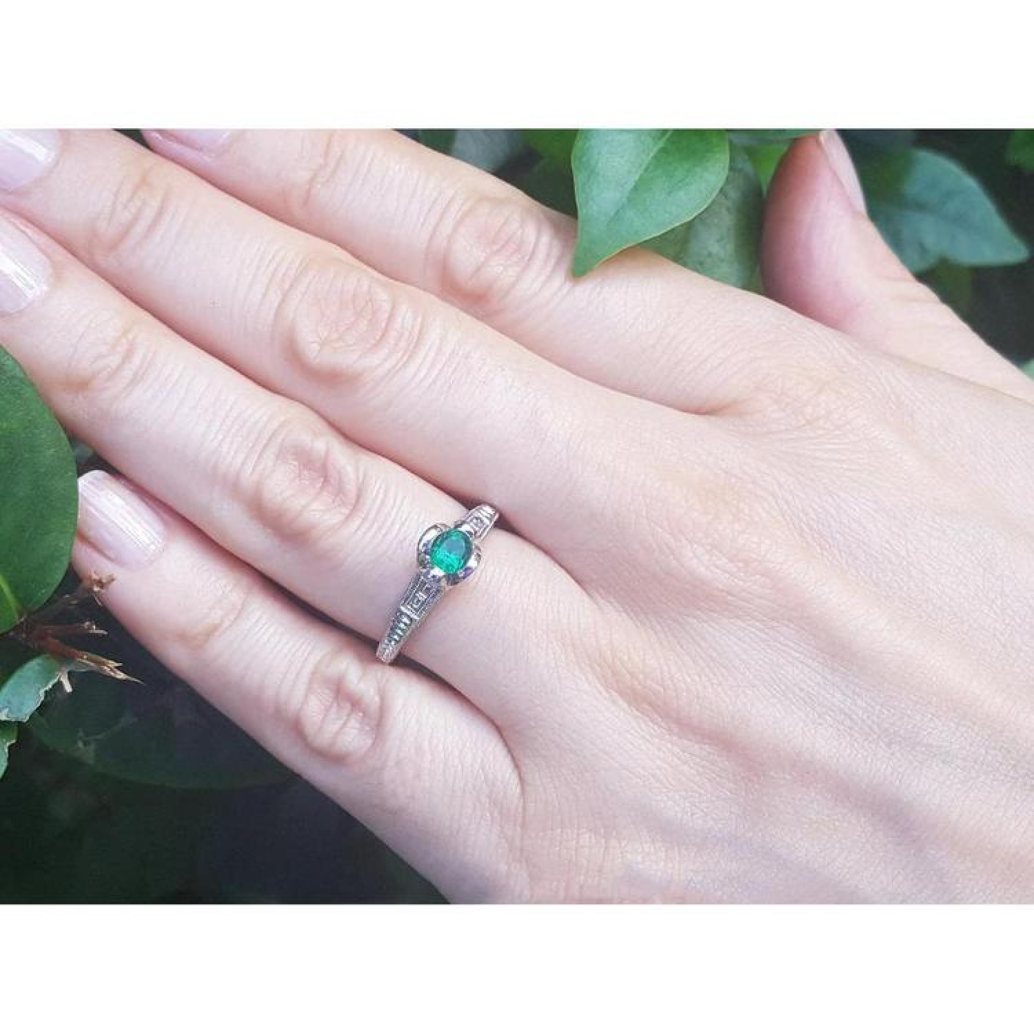 Oval-cut Colombian emerald ring with baguette diamonds in 14K white gold on a hand.
