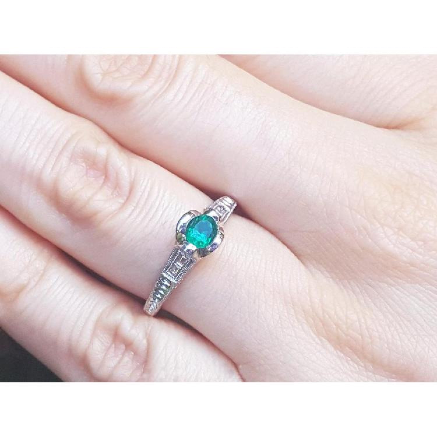 Oval-cut Colombian emerald ring with baguette diamonds in 14K white gold on a hand.