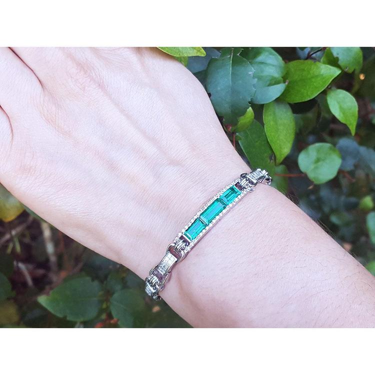 white gold bracelet with vibrant Colombian emeralds and princess cut diamonds on a wrist.
