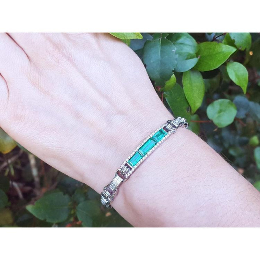 white gold bracelet with vibrant Colombian emeralds and princess cut diamonds on a wrist.