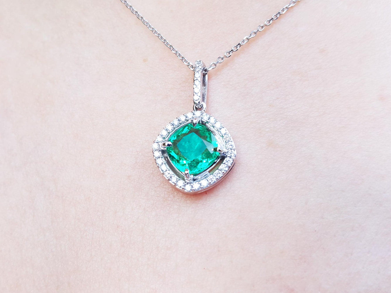 Emerald pendant necklace on a light pink background