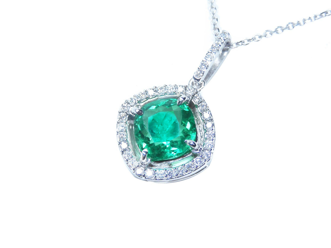 Emerald pendant necklace on a white background left side position.
