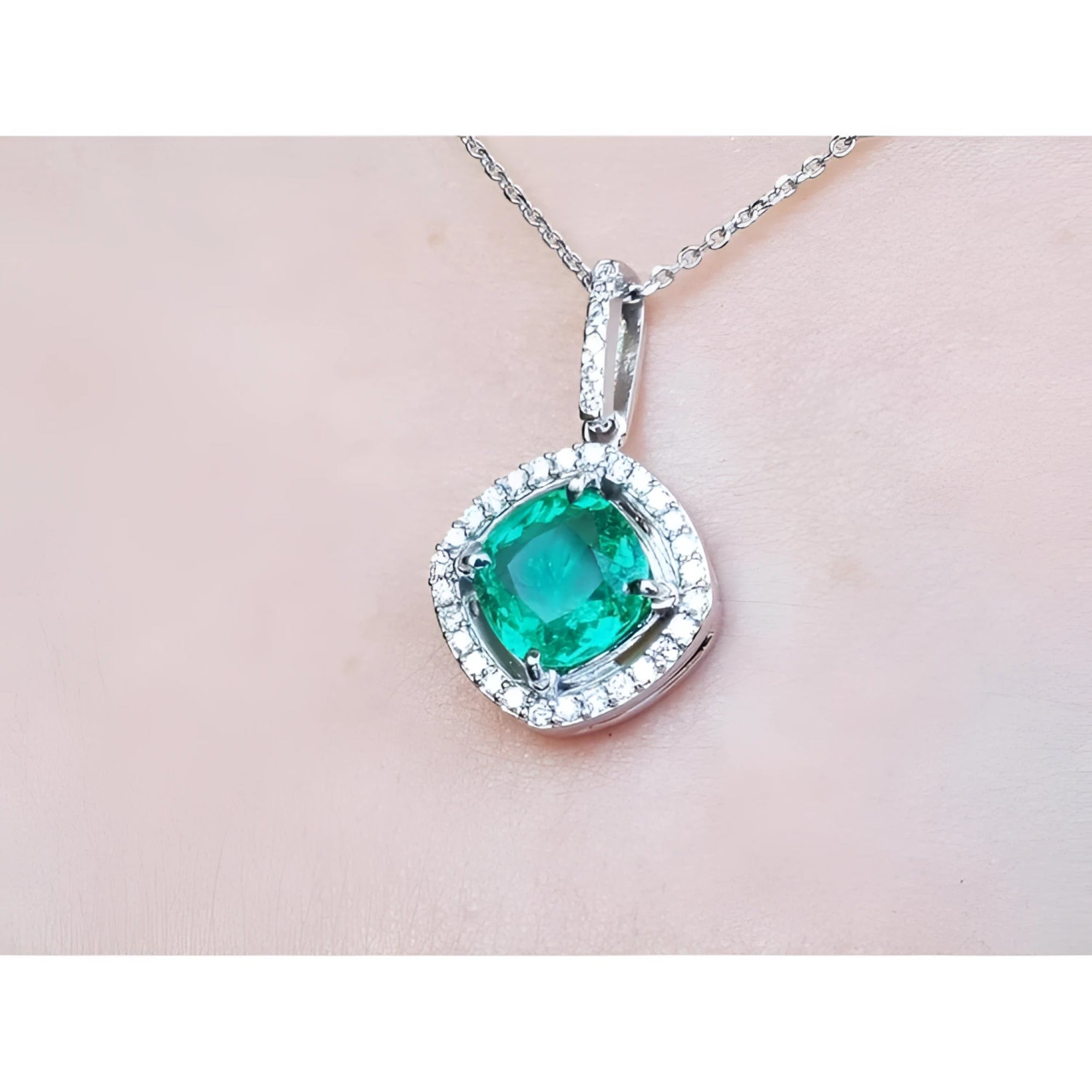 Emerald pendant with diamond accents on a light pink skin background.