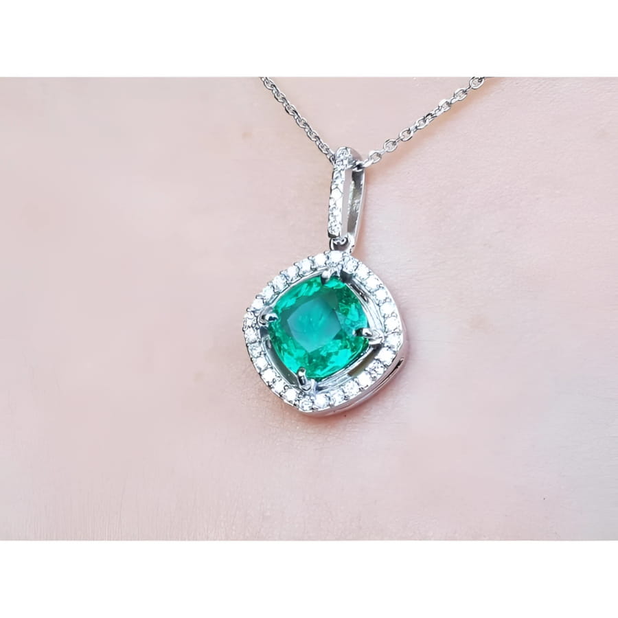 Emerald pendant with diamond accents on a light pink skin background.