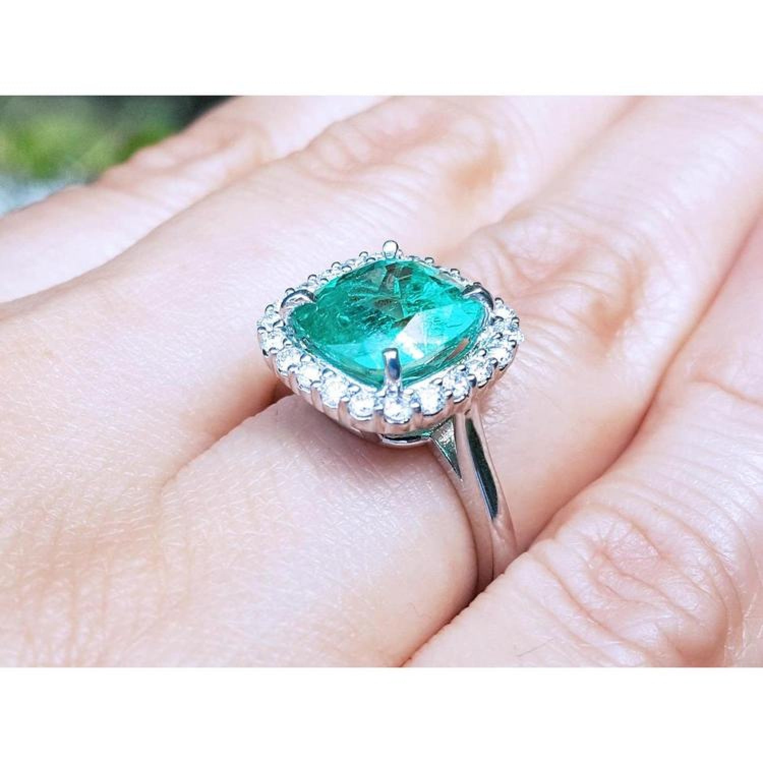 3.69 ct cushion cut Colombian emerald engagement ring with diamond halo in 18K white gold.