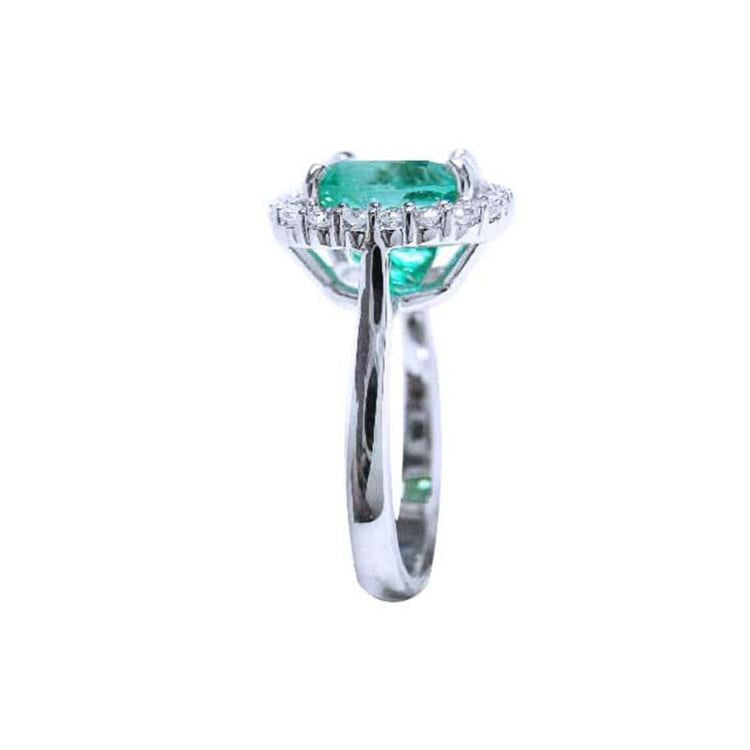 Cushion cut Colombian emerald engagement ring with diamond halo in 18K white gold.