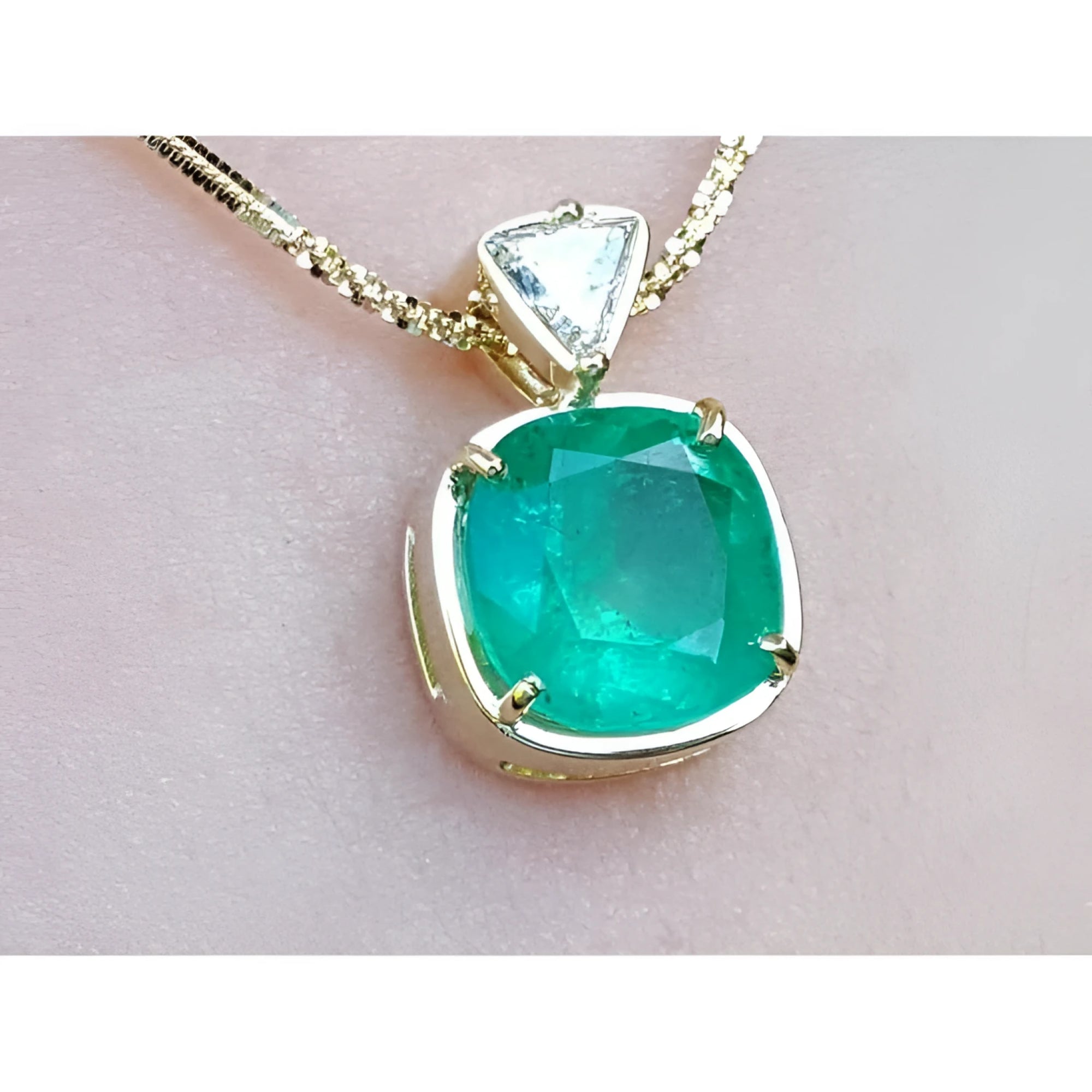 A genuine colombian emerald pendant with gold setting on a light skin background