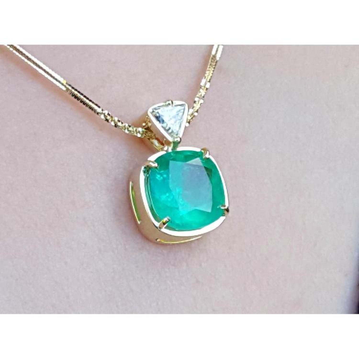 Cushion cut emerald pendant necklace with a triangular diamond accent on an 18K yellow gold chain.