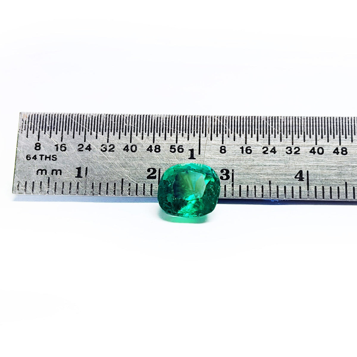 Cushion cut loose emerald from muzo Colombia, next to a ruler for measure size