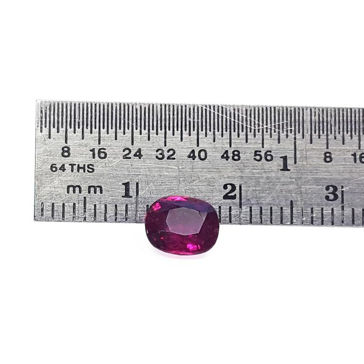 Vibrant red 1.18 carat cushion-cut natural ruby gemstone next to a ruler for scale.