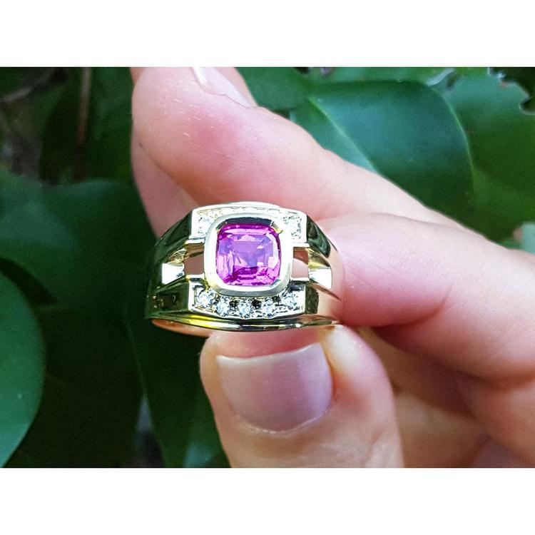 Men's 18K yellow gold ring with a bezel-set cushion-cut purplish-pink sapphire and diamond accents.
