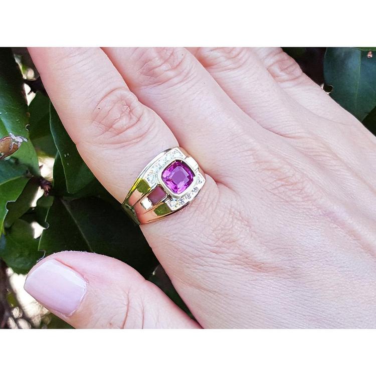 Men's 18K yellow gold ring with a bezel-set cushion-cut purplish-pink sapphire and diamond accents.