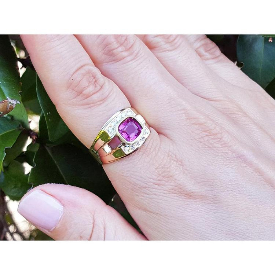 Men's 18K yellow gold ring with a bezel-set cushion-cut purplish-pink sapphire and diamond accents.