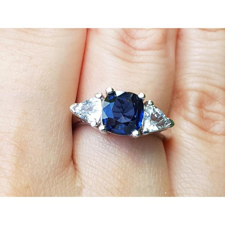 14k white gold ring with a blue cushion cut natural sapphire and two triangular sapphires on a finger