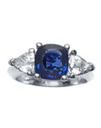 Women's cushion cut natural sapphire ring with trillion side white sapphires made of 14k white gold.