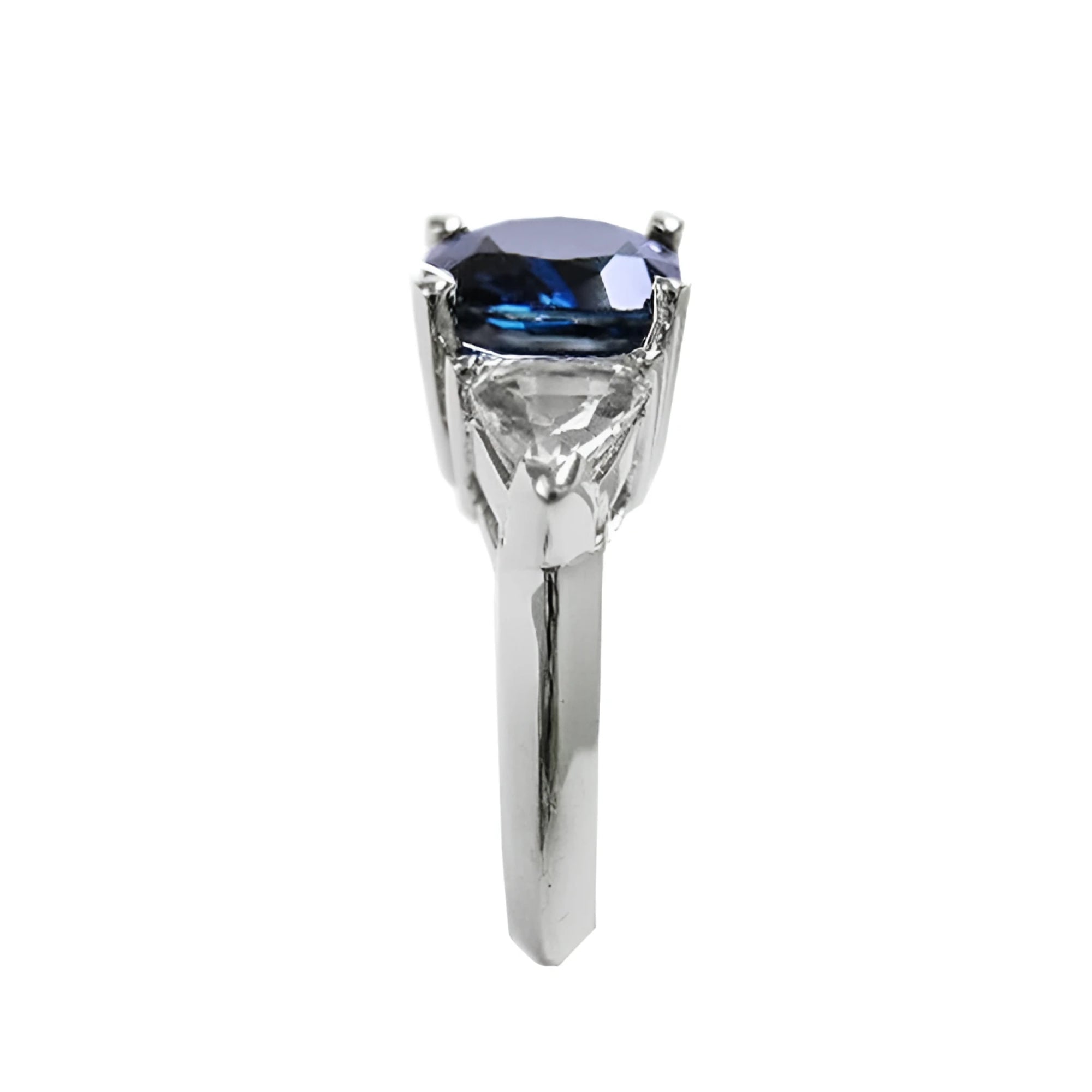 Deep blue cushion-cut sapphire ring with trillion side sapphires in white gold.