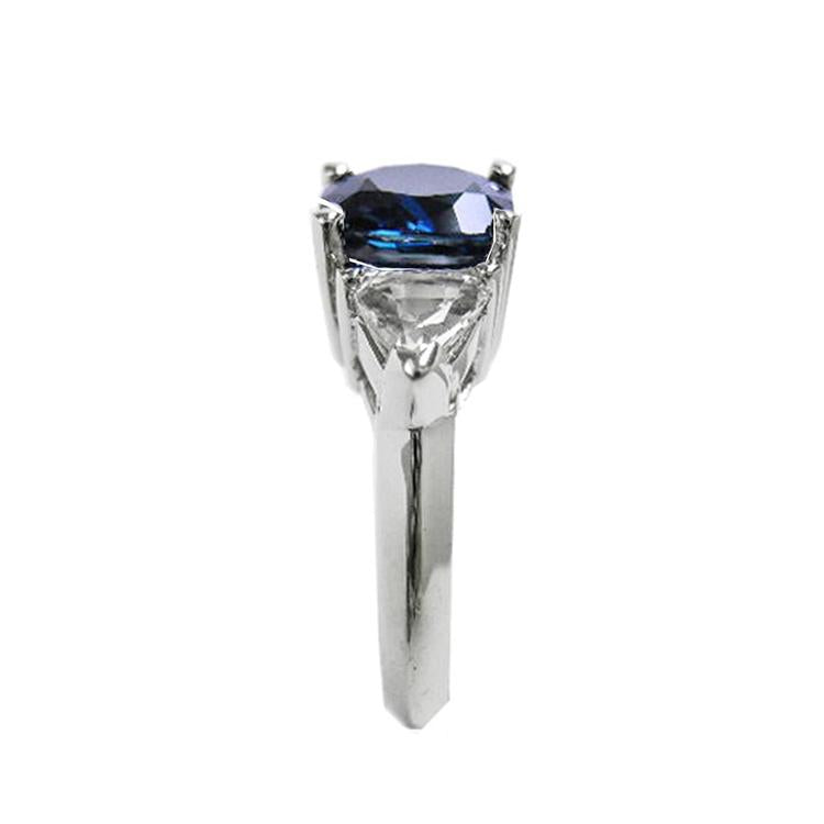 Deep blue cushion-cut sapphire ring with trillion side sapphires in white gold.