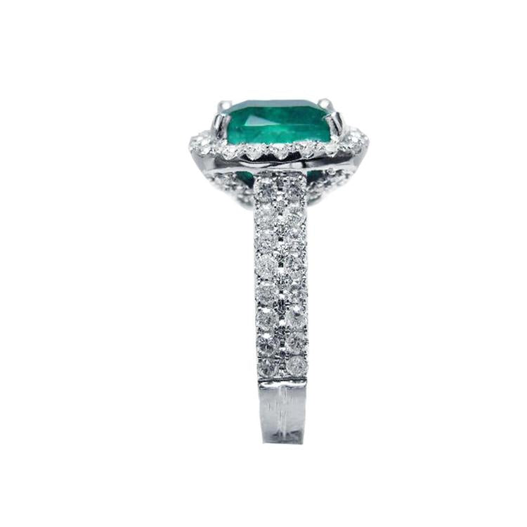 Cushion cut 3.92 ct. natural emerald ring in 14K white gold with diamond halo and pavé band.
