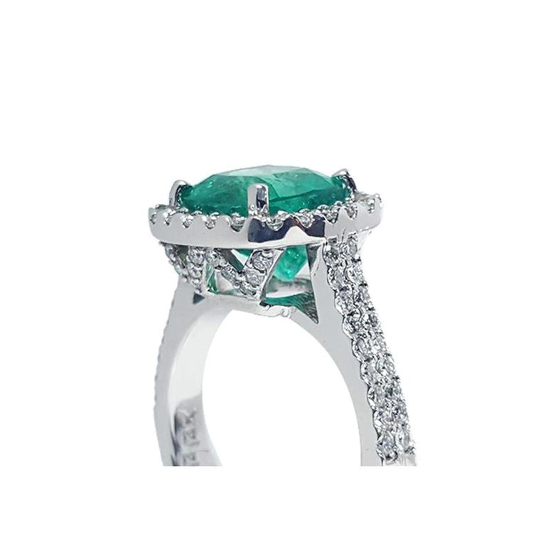 Cushion cut 3.92 ct. natural emerald ring in 14K white gold with diamond halo and pavé band.
