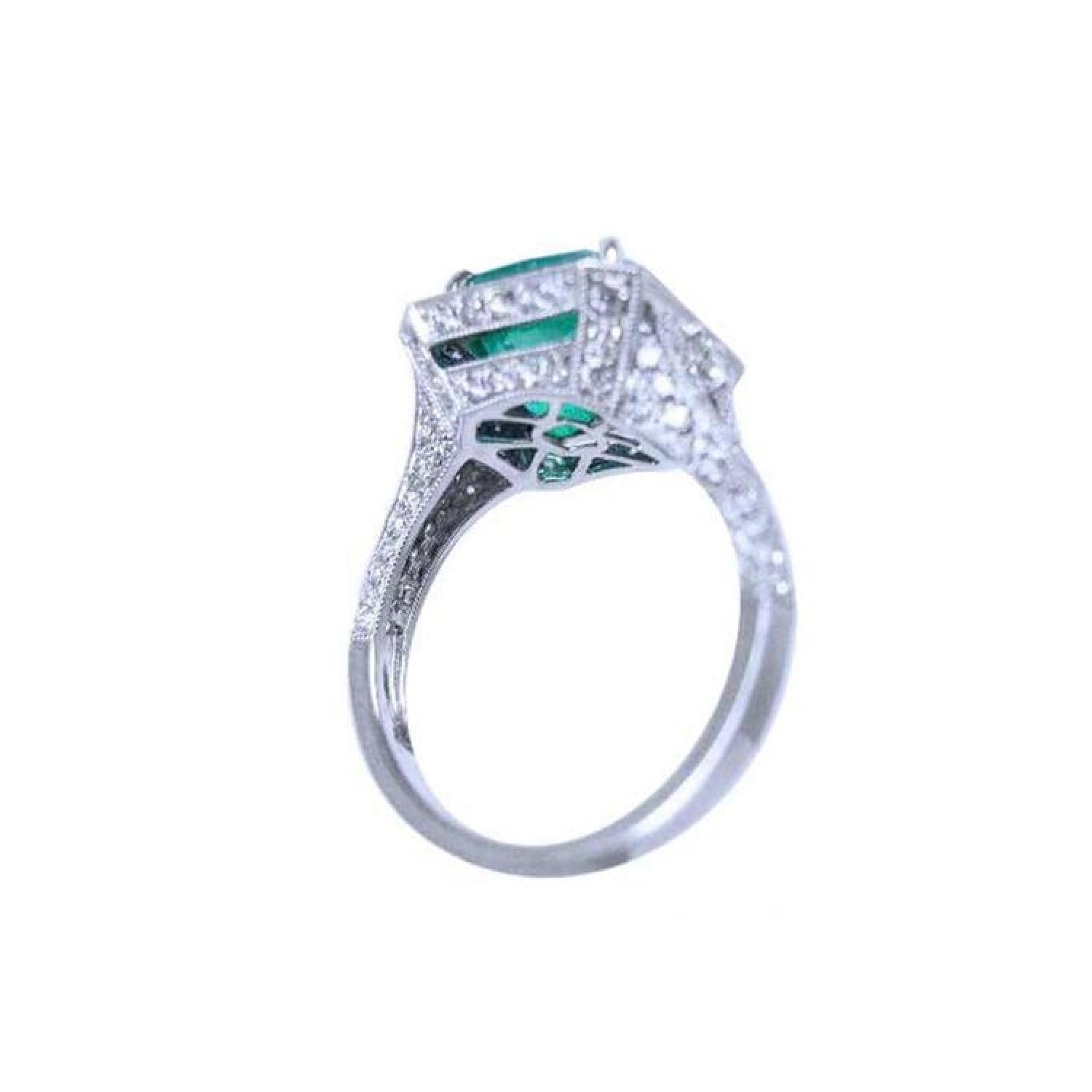 Cushion cut emerald engagement ring with diamond halo in 18K white gold.