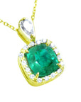A yellow gold pendant with a cushion cut natural emerald in the center surrounded by a halo diamond right side profile.