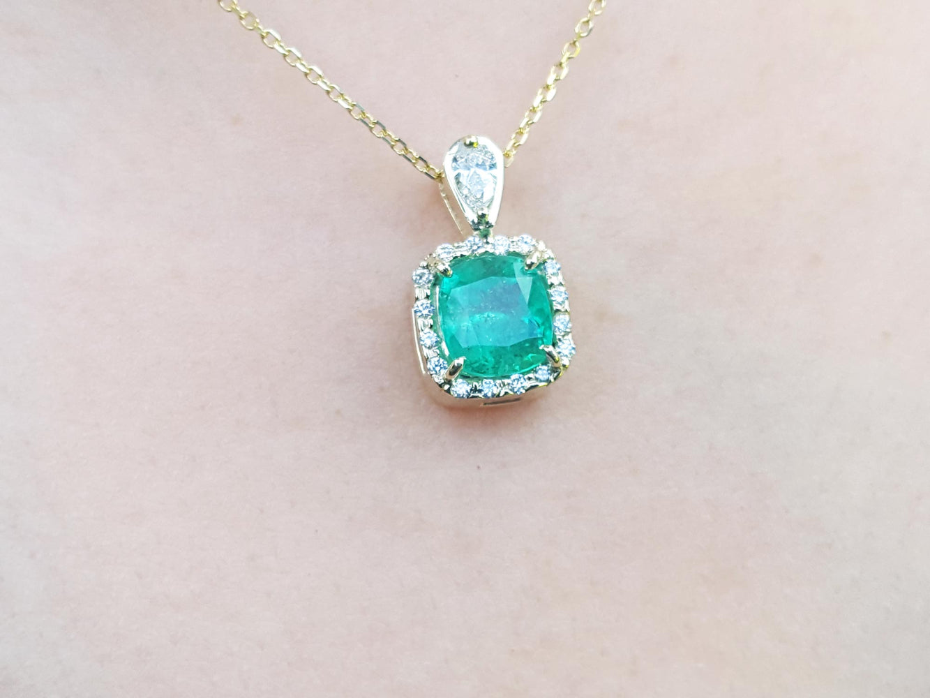 Emerald pendant necklace on a soft skin pink background,