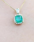 Emerald pendant necklace on a soft skin pink background,