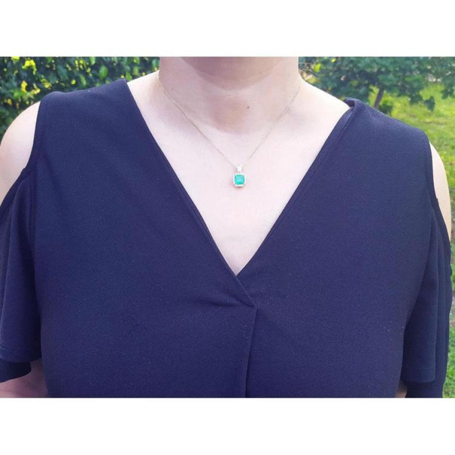 Cushion-cut emerald pendant with halo natural diamonds on a 14K yellow gold chain, worn on a model.