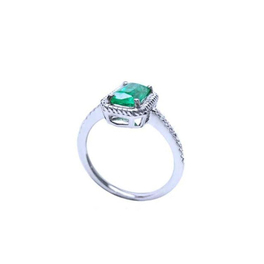14K white gold solitaire ring with a cushion-cut emerald and rope detailing.