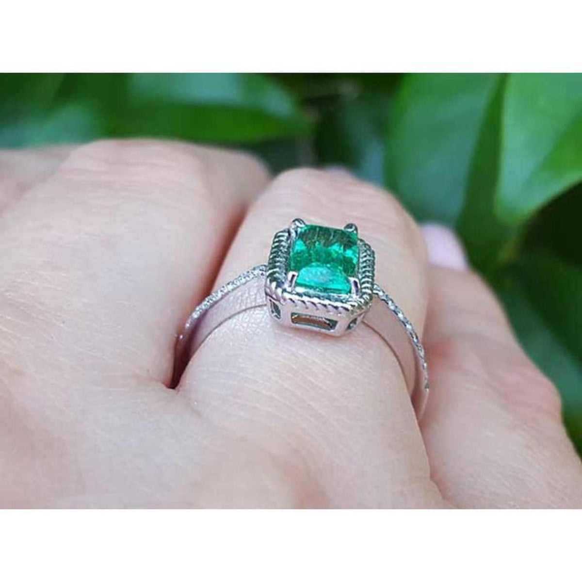 14K white gold cushion-cut emerald solitaire ring with distinctive rope detailing on a hand.