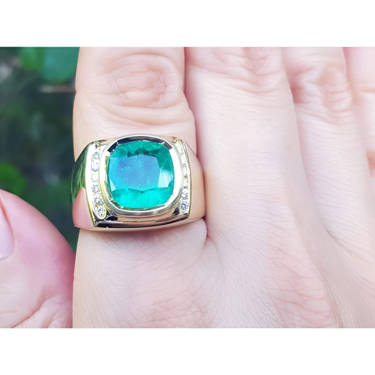 An 18k gold men’s ring featuring a cushion-cut Muzo Colombian emerald and accented with natural diamonds, elegantly worn on the finger.