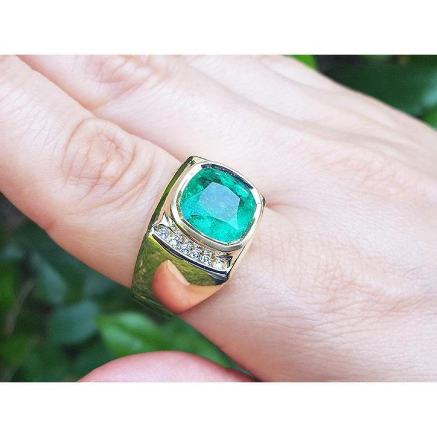 Men's 18k yellow gold ring with a cushion-cut emerald and two rows of channel-set diamonds.