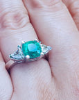 Brides' engagement ring cushion cut trillion side diamonds on a finger.