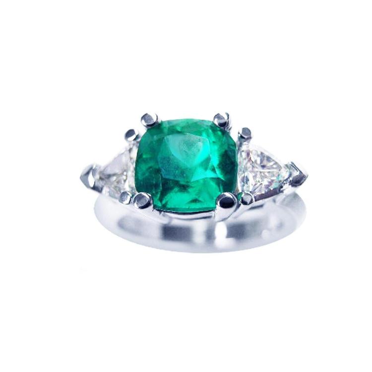 A cushion cut Muzo colombian emerald ring with trillion side natural diamonds, crafted in 1 4k white gold.