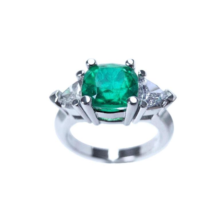 Emerald cushion cut trillion accent diamonds ring for women on a white background.